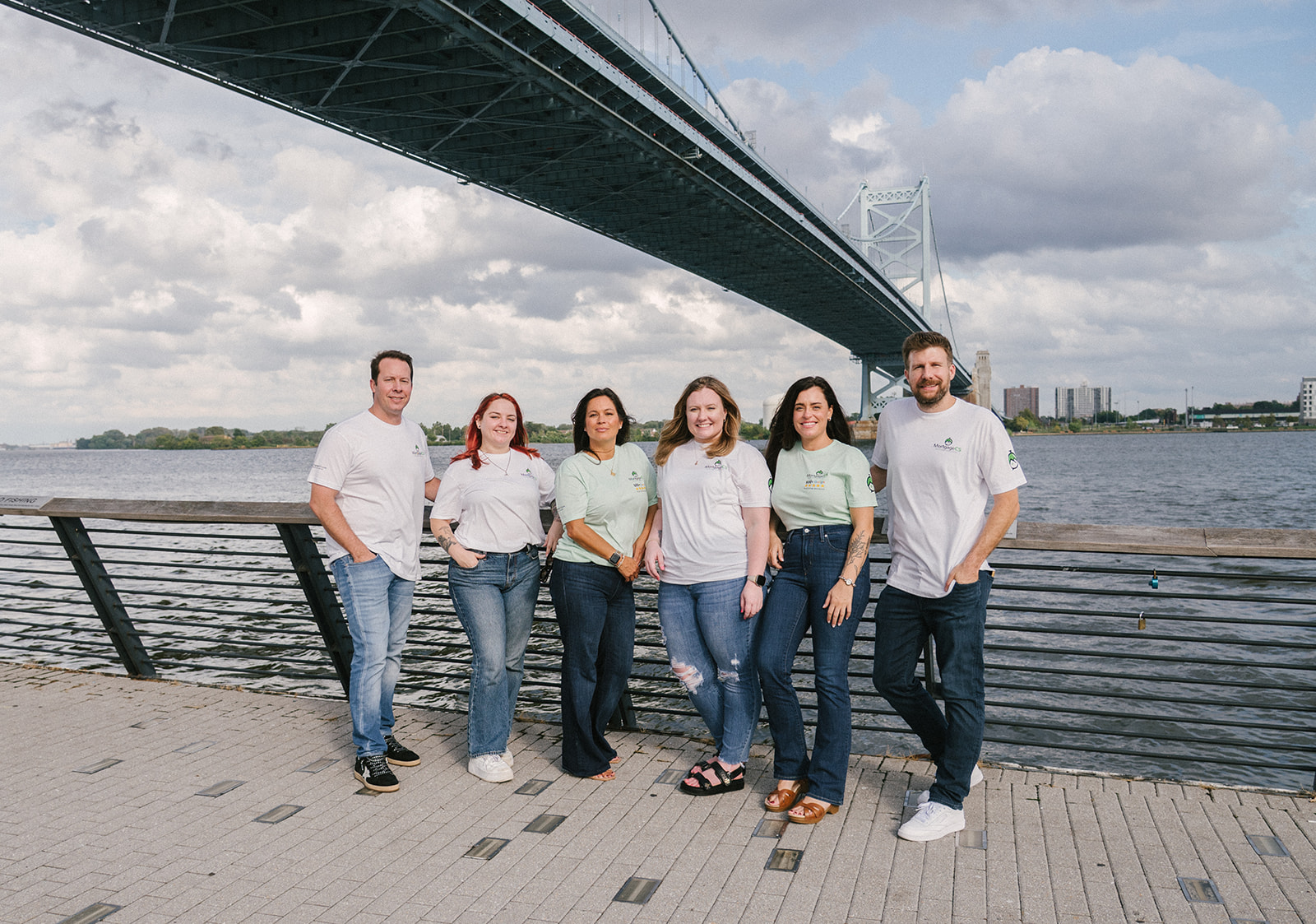 The MortgageCS team standing together under the Ben Franklin Bridge in Philadelphia